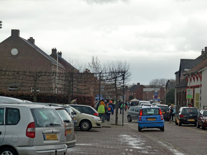Wandelaars in Vleutstraat op weg naar gemeenschapshuis de Koppel. Bovendien veel volgers in auto's die de straat versperren.