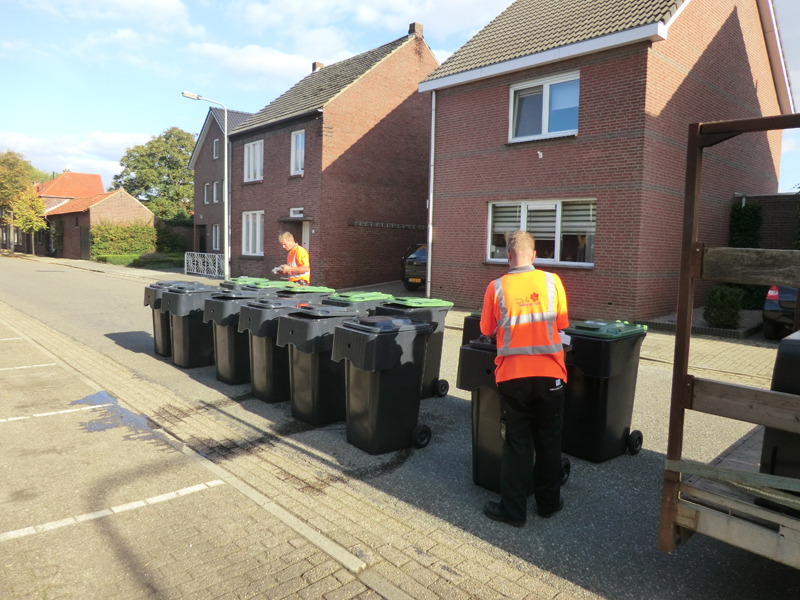 Medewerkers van DVL Milieuservice monteren de containers en voorzien deze van (adres-)stickers