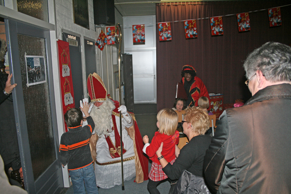 De Sint verlaat de zaal groet enkele kinderen met high five