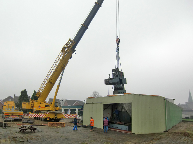 Zware machine hangt boven fabrieksgebouw